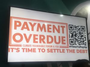 A Sign from COP27 that says "Payment Overdue: It's Time to Settle the Debt"
